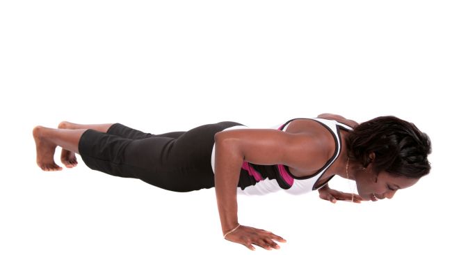 Woman performing full push ups from her toes in a plain white background