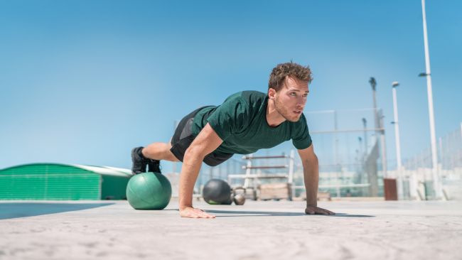 Man performing stability ball press ups outside the gym