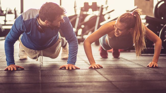 Man and woman performing push ups in the gym